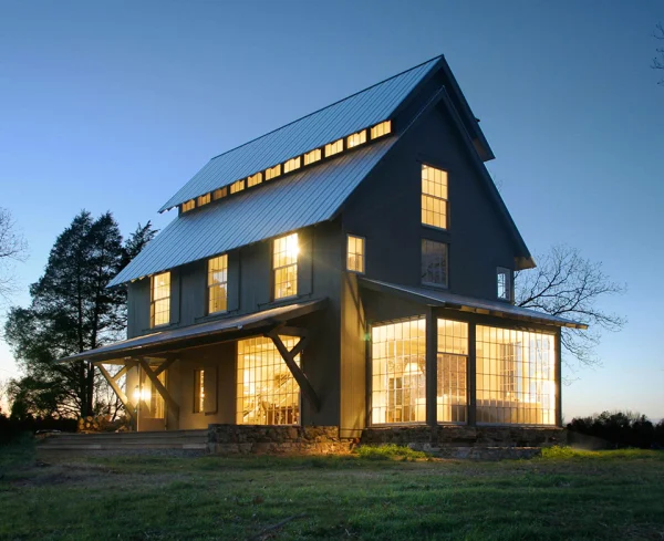 farmhouse at dusk with lights shining through window