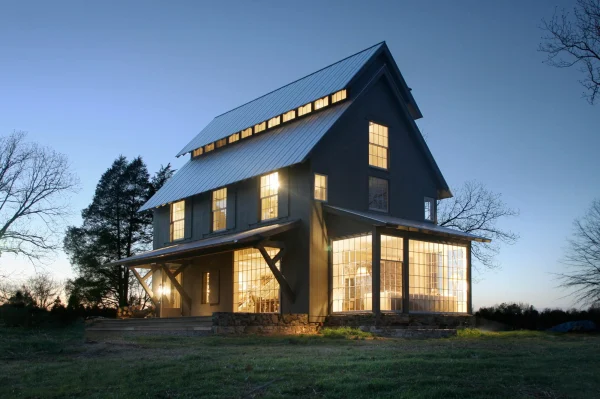 Farmhouse at dusk with light shining through the windows